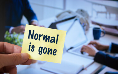 A male hand holding a sticky note written Normal is gone.