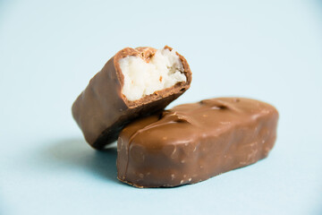 Delicious chocolate bars with coconut flakes on a blue background