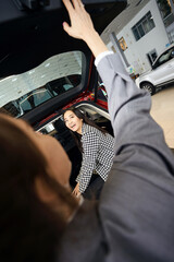 Happy curious lady sitting in car trunk