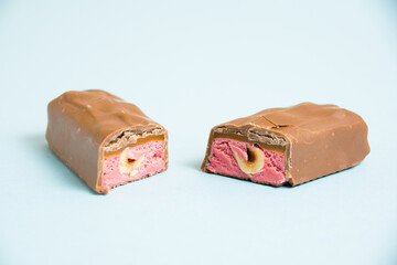 Tasty chocolate bar with whole hazelnut and strawberry on a blue background