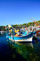 A blue nautical fishing vessel moored in the crystal-clear waters of Niel, under a perfect sky