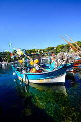 Obraz premium A blue nautical fishing vessel moored in the crystal-clear waters of Niel, under a perfect sky