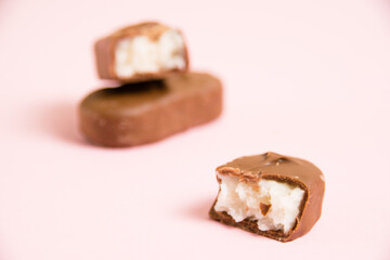 Sweet chocolate bar with coconut flakes macro on pink paper background with copy space
