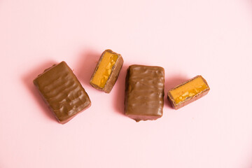 Flatlay, sweet chocolate bar with salted caramel macro on pink paper background with copy space