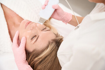 Woman on anti-aging ultrasonic facial cleansing procedure