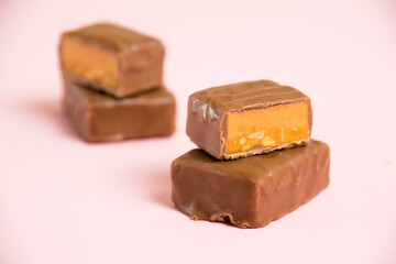 Sweet chocolate bar with salted caramel macro on pink paper background with copy space