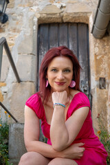 mature woman with red hair in front of a old door