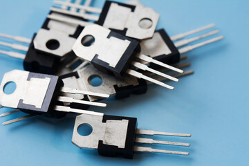 Pile of field-effect transistors on blue surface background. Selective focus