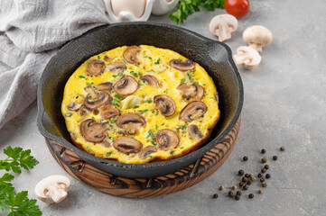 Omelette with mushrooms and herbs in a pan on a white wooden background. Healthy breakfast. Top view. Copy space.