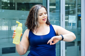 Fitness Wearables, fitness trackers and smartwatches for tracking training performance. Plus size fitness woman looking at hands fitness trackers