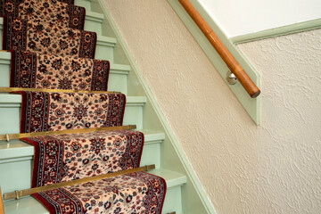 Vintage wooden staircase with antique carpet runner close-up, retro design. steps of a staircase in antique home