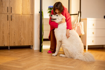 Dog meets its owner at the doorway of living room at home, huggnig together. Concept of a happy...