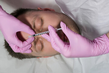 Obraz na płótnie Canvas Man during surgery filling facial wrinkles