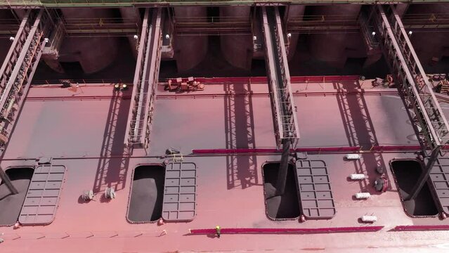 Conveyor belts loading iron taconite into open hatches of large freight ship on ore dock