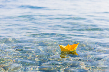 Yelow paper boat sailing on blue water surface	
