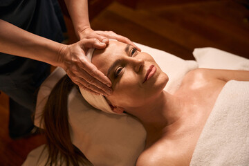 Fototapeta na wymiar Experienced massage therapist stimulating acupoint on woman face