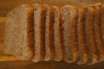 close-up toast appetizing fresh wholemeal bread with bran sliced in layers on wooden board, wheat, multigrain bread topview, bakery pastries, gluten products, diet, wholesome food, healthy eating
