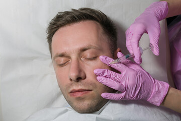 An Anonymous Female Beautician Giving Male Patient Botox Injection In Forehead. Anti Aging Treatment: Side view of mature man receiving botulinum toxin injection at medical clinic.