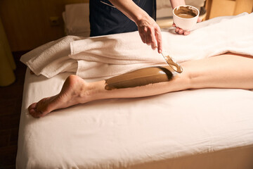 Wellness center beautician carrying out algae body wrap on client