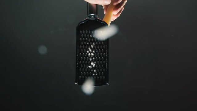 Cheese slowly rub on a metal grater on a wooden table.  The concept of cooking ingredients for pizza.  Slow motion.