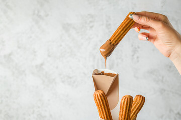 Woman taking churros from a cone and dipping it in chocolate sauce