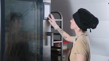 the baker girl touches the oven control panel with her finger.