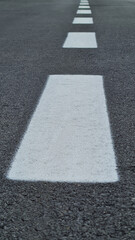 Level asphalted road with a dividing white stripes. The texture of the tarmac, top view. High quality photo