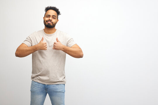 Young handsome man with beard over white background approving doing positive gesture with hand, thumbs up smiling and happy for success. Winner gesture