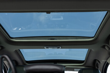 Panoramic glass sun roof in the modern car. Panoramic view inside car - double sunroof hatch with tinted glass. Sliding panoramic sunroof and luxurious leather seats