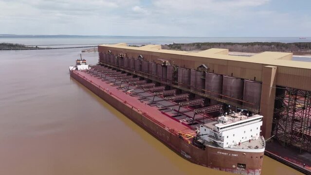 Large freight vessel at ore dock loading natural iron taconite resources for exportation along trade route