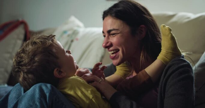 Portrait of Mother and her Toddler Son Playing Together at Night in Living Room. Cheerful and Playful Woman Enjoying Time with her Baby, Tickeling Him Concept of Family Bonds and Affection
