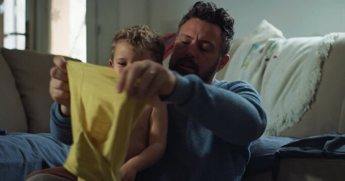 Portrait of a Man Trying to Manage his Toddler Son While He is Throwing a Tantrum at Home. Male Child Screaming and Crying While his Father Tries to Get him Dressed. Parenting Concept