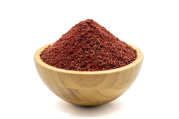 Sumac isolated on white background. Dried ground red Sumac powder spices in wooden bowl