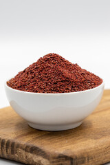 Sumac isolated on white background. Dried ground red Sumac powder spices in wooden bowl. Close up