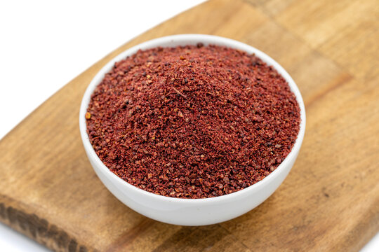 Sumac isolated on white background. Dried ground red Sumac powder spices in wooden bowl