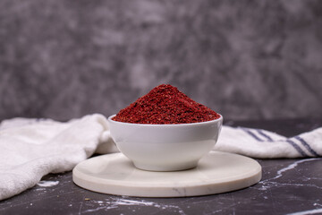 Sumac on dark background. Dried ground red Sumac powder spices in wooden bowl
