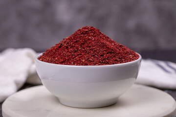 Sumac on dark background. Dried ground red Sumac powder spices in wooden bowl. Close up