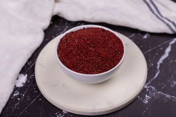 Sumac on dark background. Dried ground red Sumac powder spices in wooden bowl