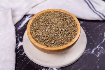 Dried crushed basil on dark background. Dried ground basil powder spices in wooden bowl. Spice concept