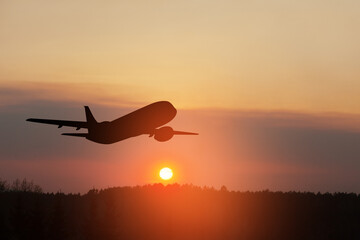 Airplane taking off at the sunset sky.