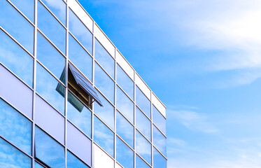 Fototapeta na wymiar Modern glass office building against blue sky background in low angle and perspective side view