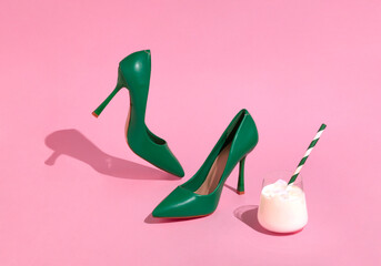 Creative scene of women's green shoes and white cocktail. High heel shoes on sunny day and pink background.