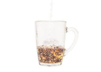 Adding hot water to a transparent cup with black tea leaves. Darjeeling tea. Shooted in motion. On a white background.