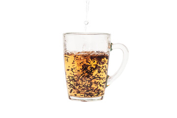 Adding hot water to a transparent cup with black tea leaves. Darjeeling tea. Shooted in motion. On a white background.