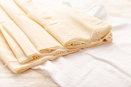 Raw phyllo pastry, thin filo dough for baking, for pie and cakes on wooden kitche table