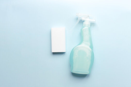 .Flat lay cleaning spray and sponge on blue background. Tidy up, cleanliness