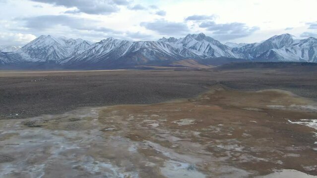 Aerial Cinematic drone Mammoth Lakes California Sierra Nevada  hilltop hot spring field and mountain landscape late after sunset up skier snowboarders soak camp to backwards reveal pan up movement
