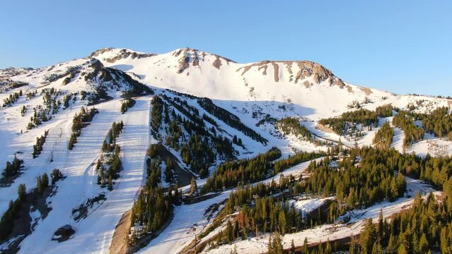 Aerial Cinematic drone early sunrise Spring Mammoth Mountain California ski trails and ski lodge parking lot gondola and chair lift to the left circling movement