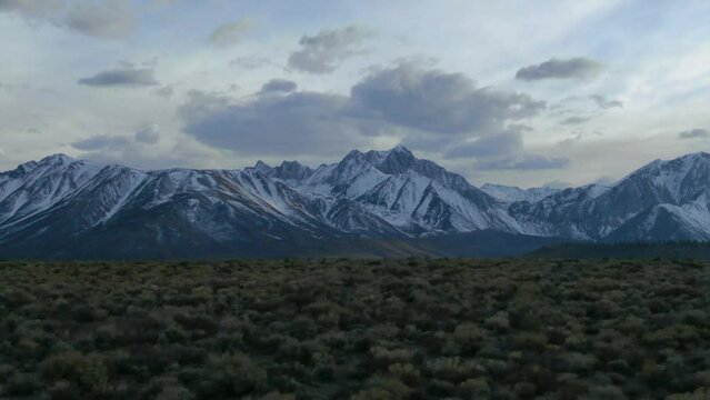 Aerial Cinematic drone Mammoth Lakes California Sierra Nevada  hilltop hot spring field and mountain landscape late after sunset up to the right movement