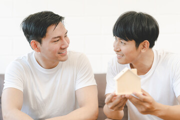 Asian Gay Couple Buying New Dream House Or Property with house model. Concept for marriage, loan, finance, insurance, mortgage, real estate and property.